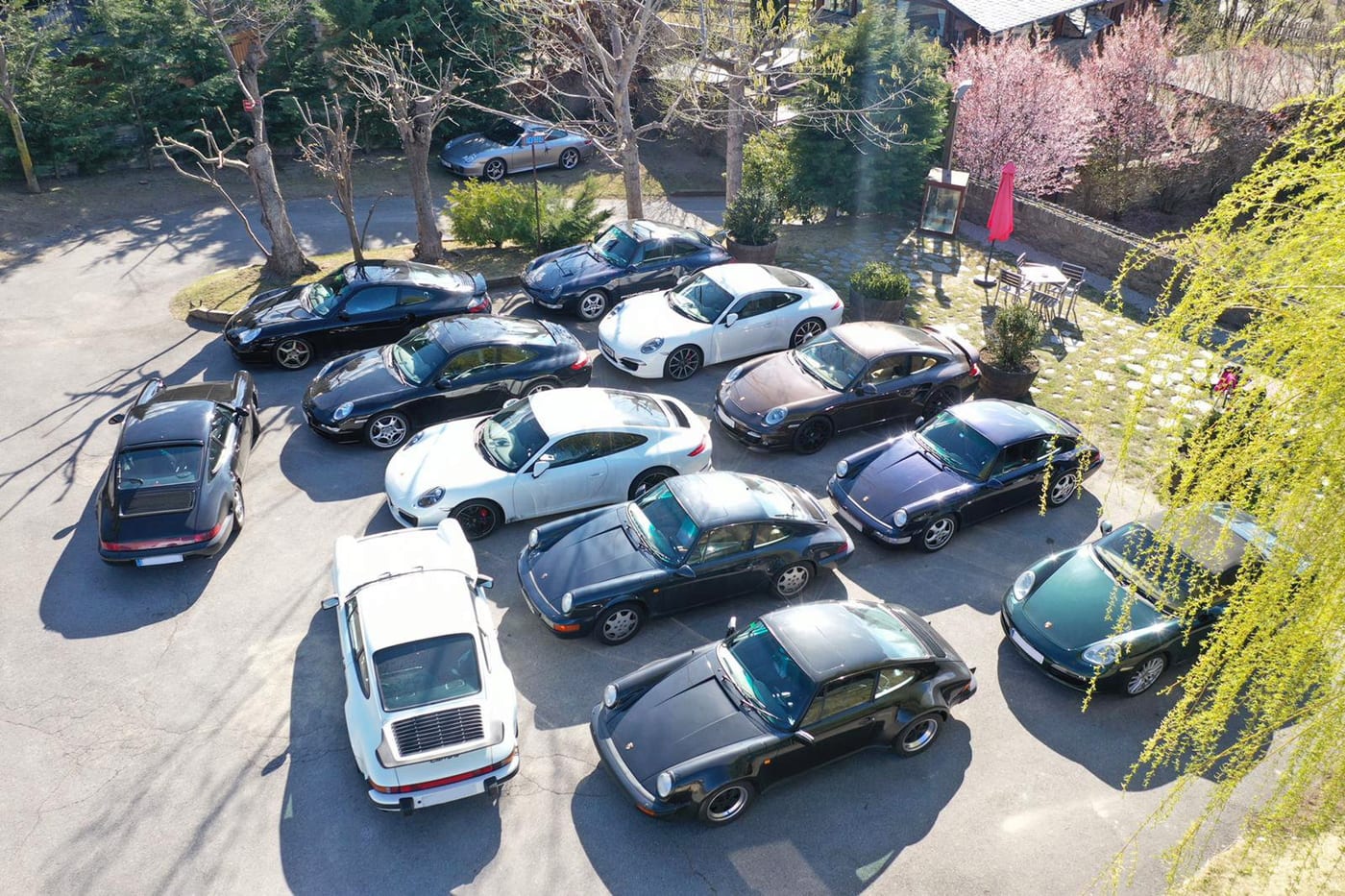 Vista zenital d'una quinzena de Porsche del V Endurance aparcats, d'un 930 Turbo blanc a un 991
