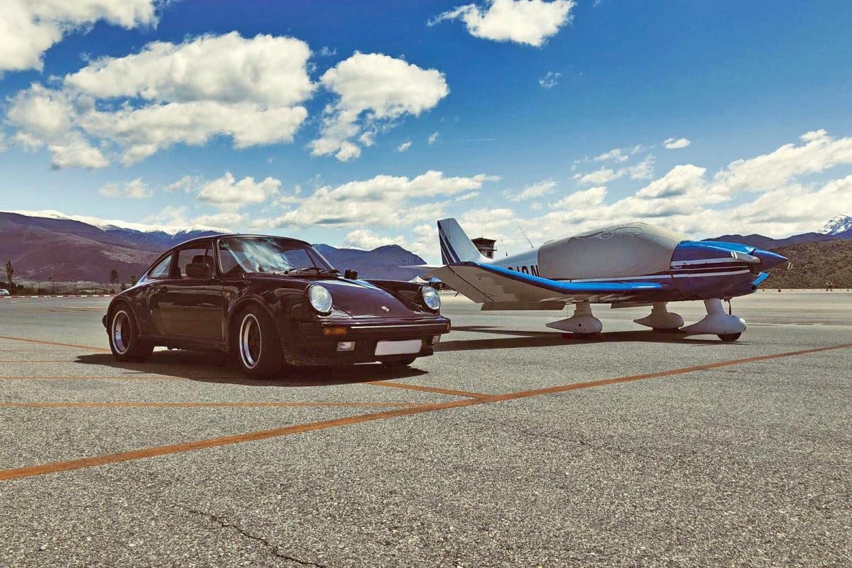 Un 911 Turbo negre al costat d'una avioneta a la pista, amb la serra nevada al fons, a The Grand Tour