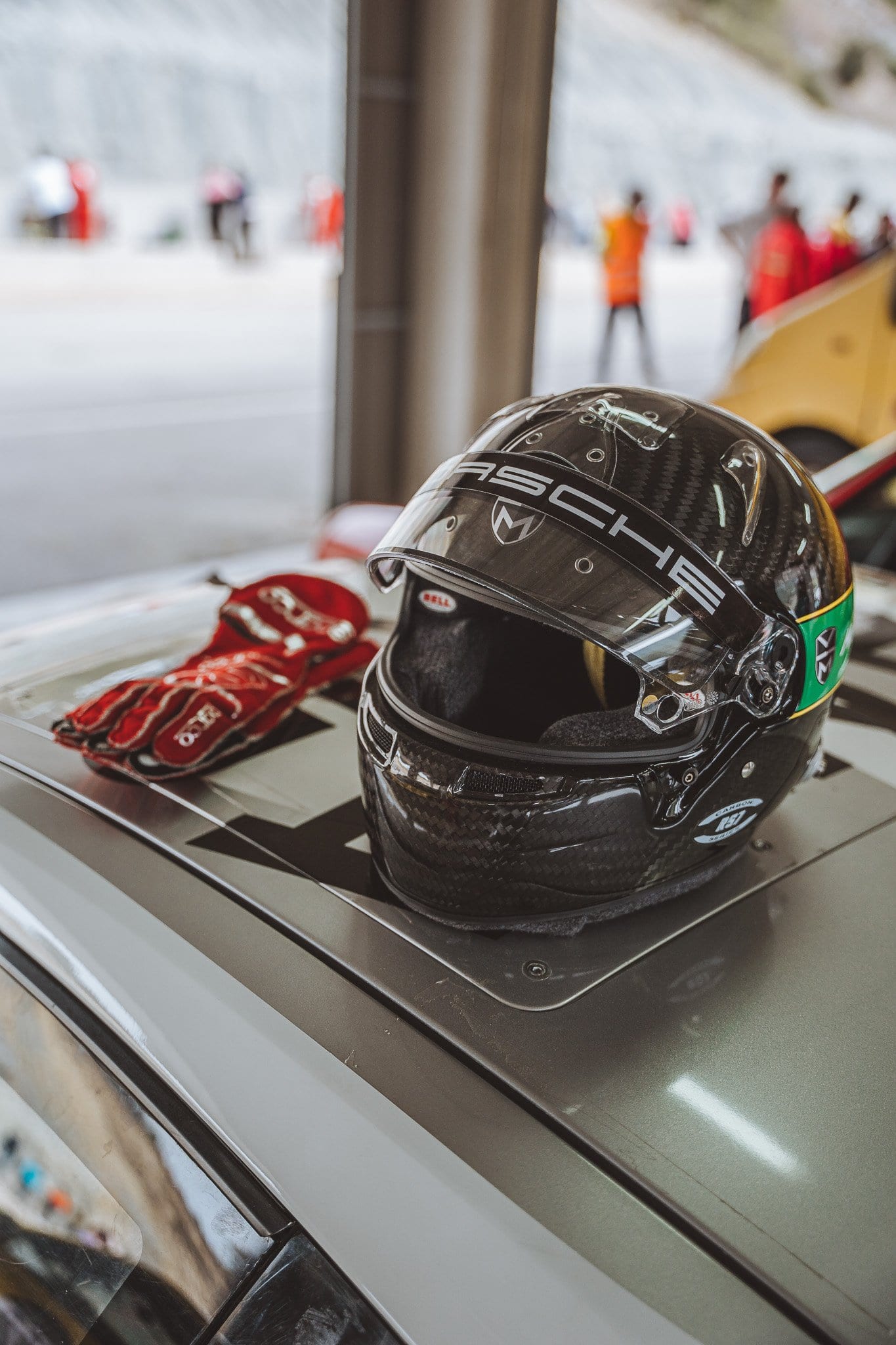 Casco y guantes del piloto sobre el capó, con el box al fondo