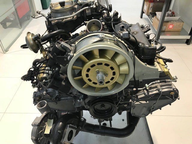 Motor bóxer con inyección mecánica y turbina dorada, sobre el soporte