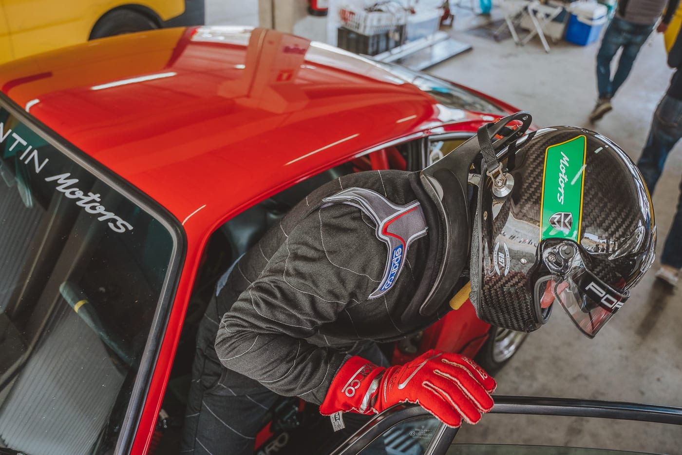 El piloto con casco y guantes rojos junto al 964 en el box