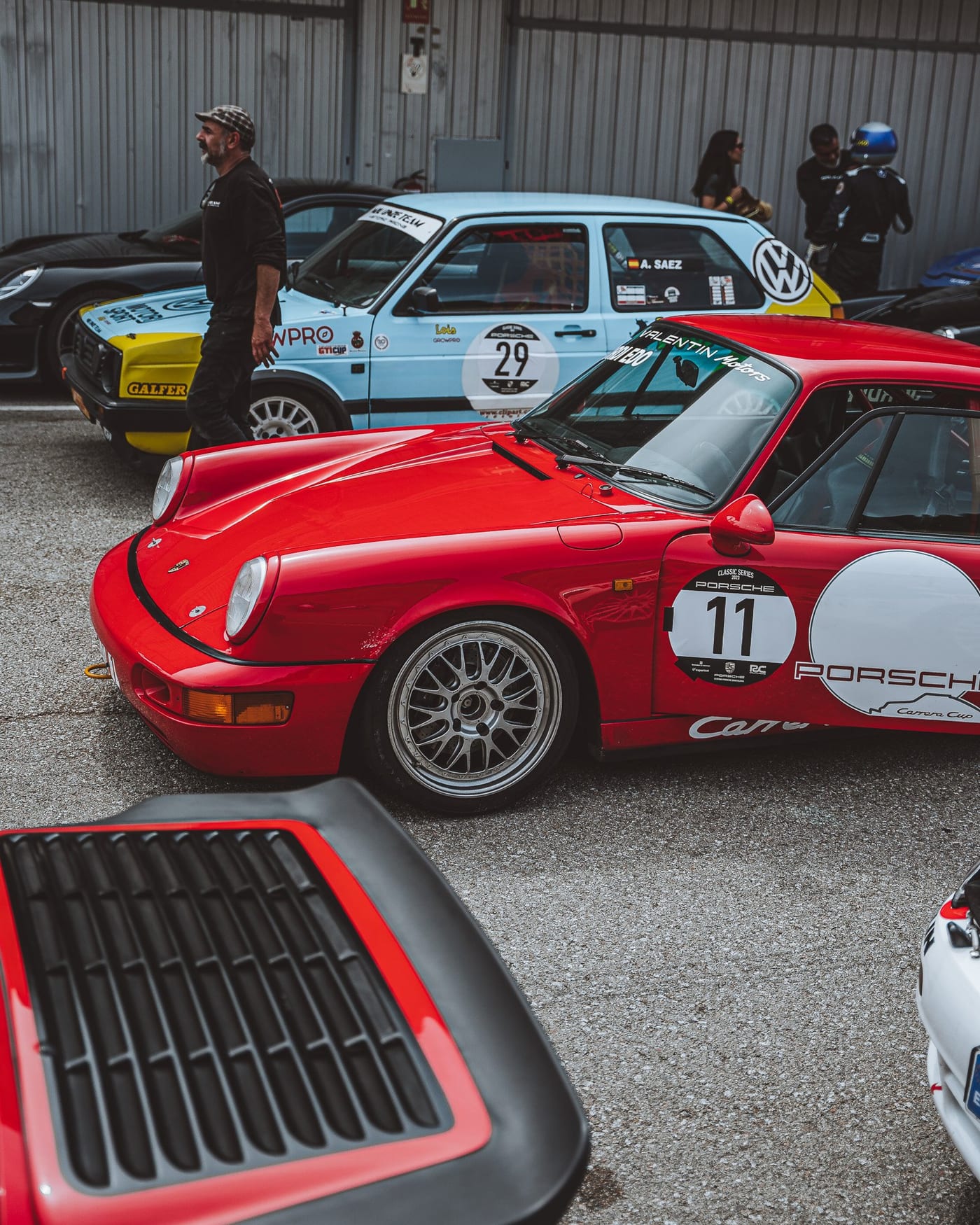 El 964 número 11 aparcado en el paddock junto a los coches de otros participantes