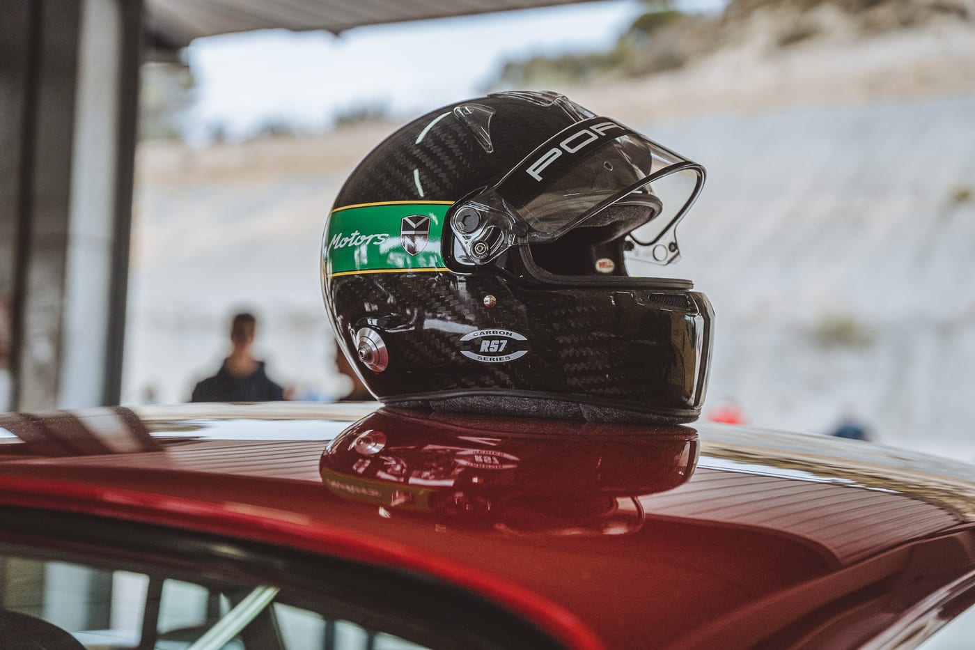 El casco descansando sobre el alerón trasero del 964 rojo, entre mangas