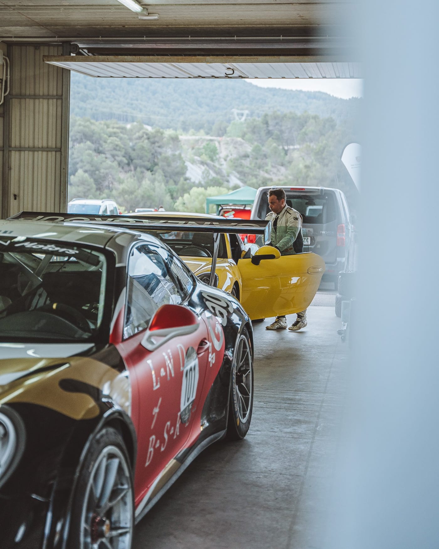 El 911 rotulado de Valentín Motors en el box, con un Cayman amarillo al fondo