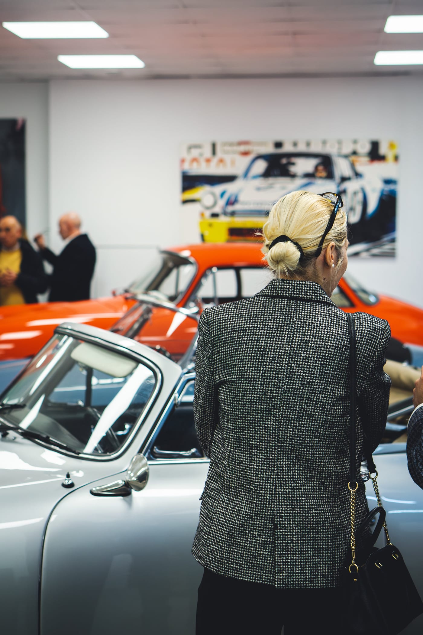 Un'ospite contempla una 356 accanto alla 911 da corsa arancione