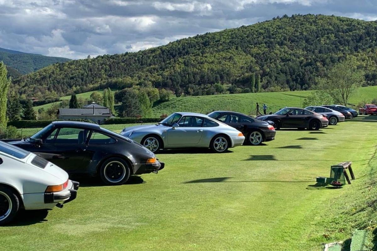 Els Porsche de The Grand Tour aparcats sobre la gespa, amb la vall i el bosc al darrere