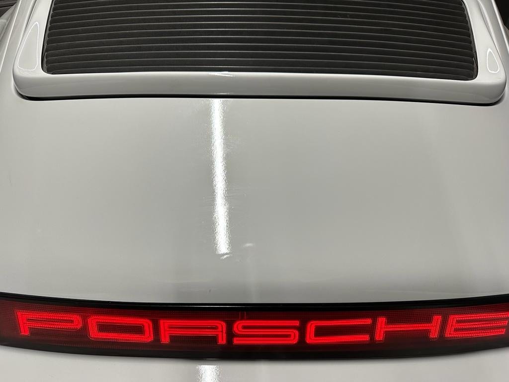 Zaga del 964 blanco con la rejilla del motor y la banda luminosa PORSCHE encendida