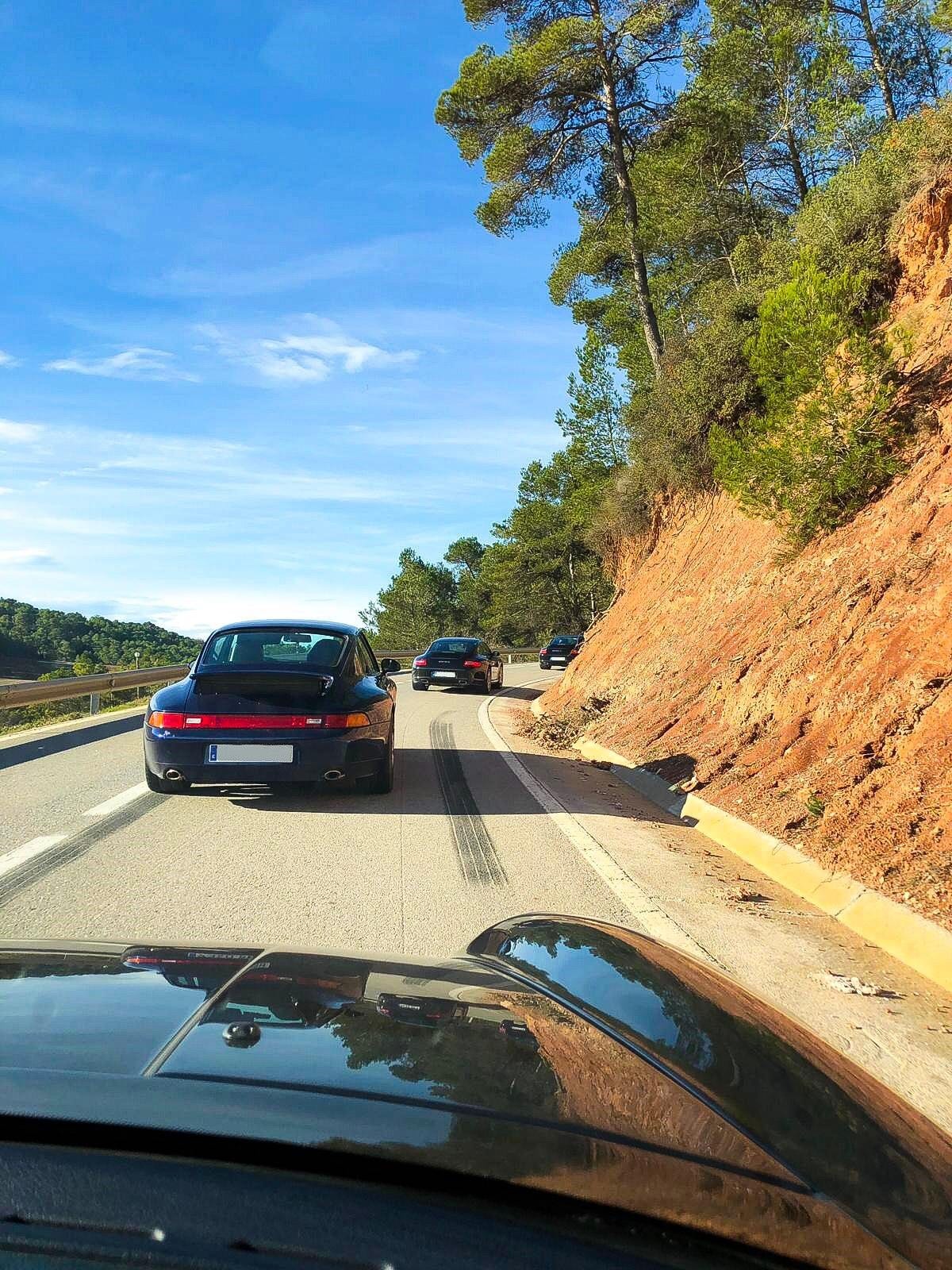 Un 993 blau marí obre la marxa per una carretera de corbes entre pins, al III Endurance