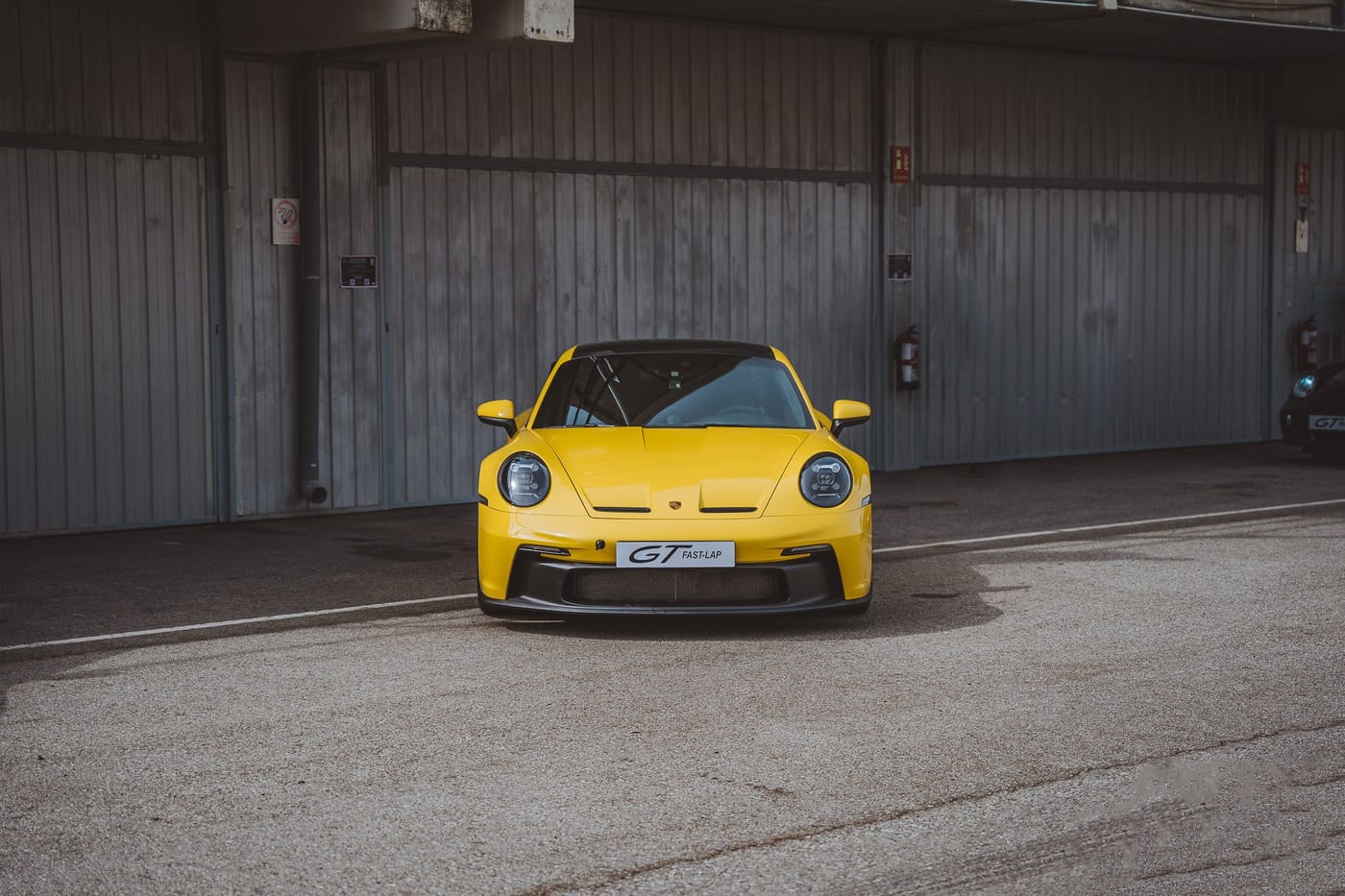 Frontal del Cayman GT4 amarillo delante del box, con el difusor a la vista