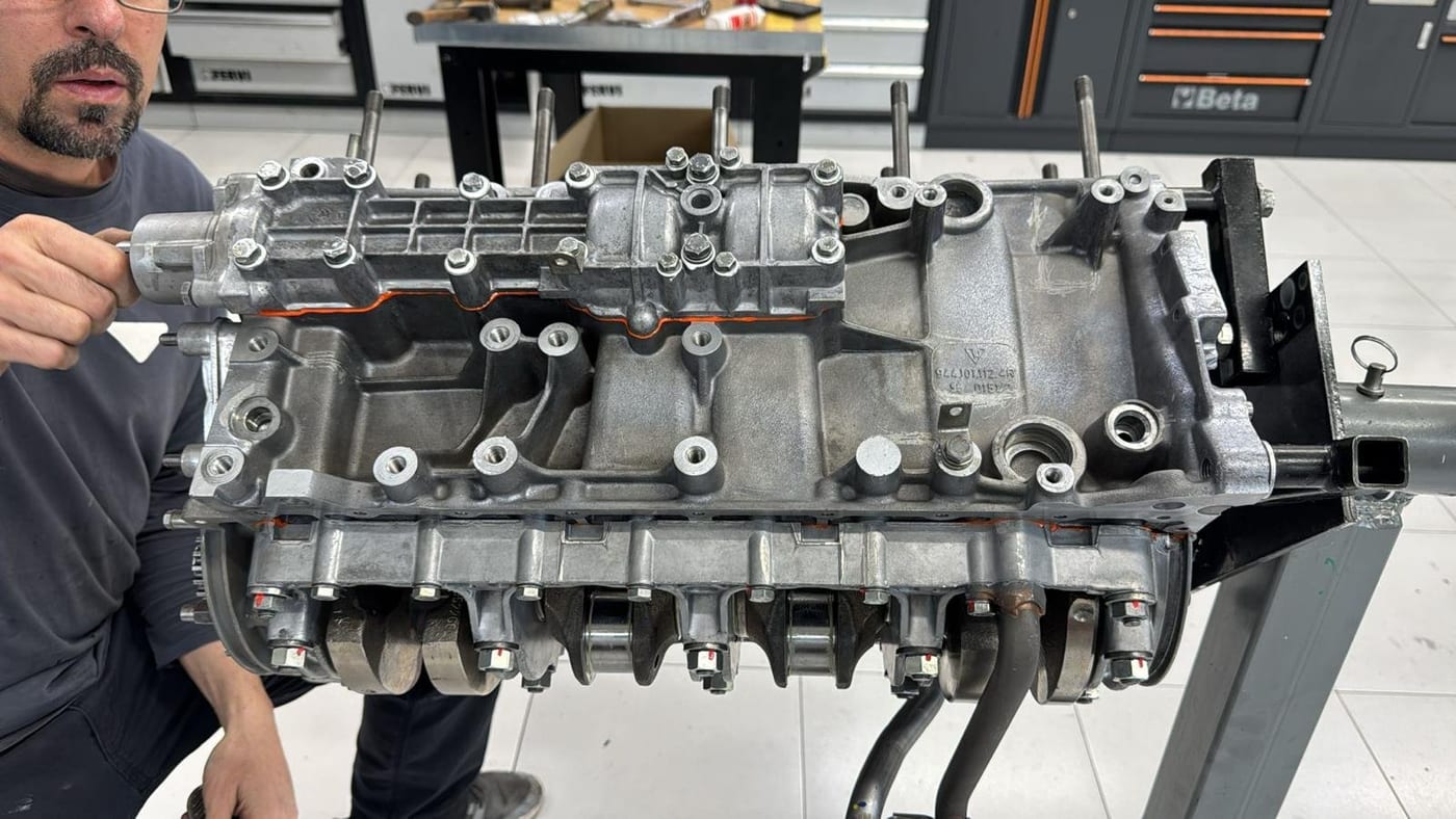 Un técnico sostiene la culata de un motor bóxer en el taller