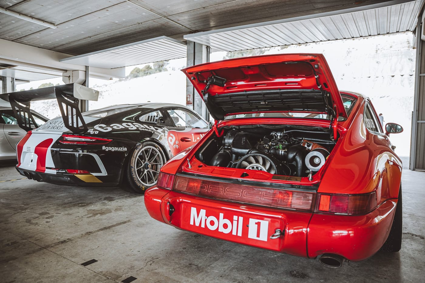 El 964 rojo con el motor al descubierto dentro del box, junto al 991 Cup