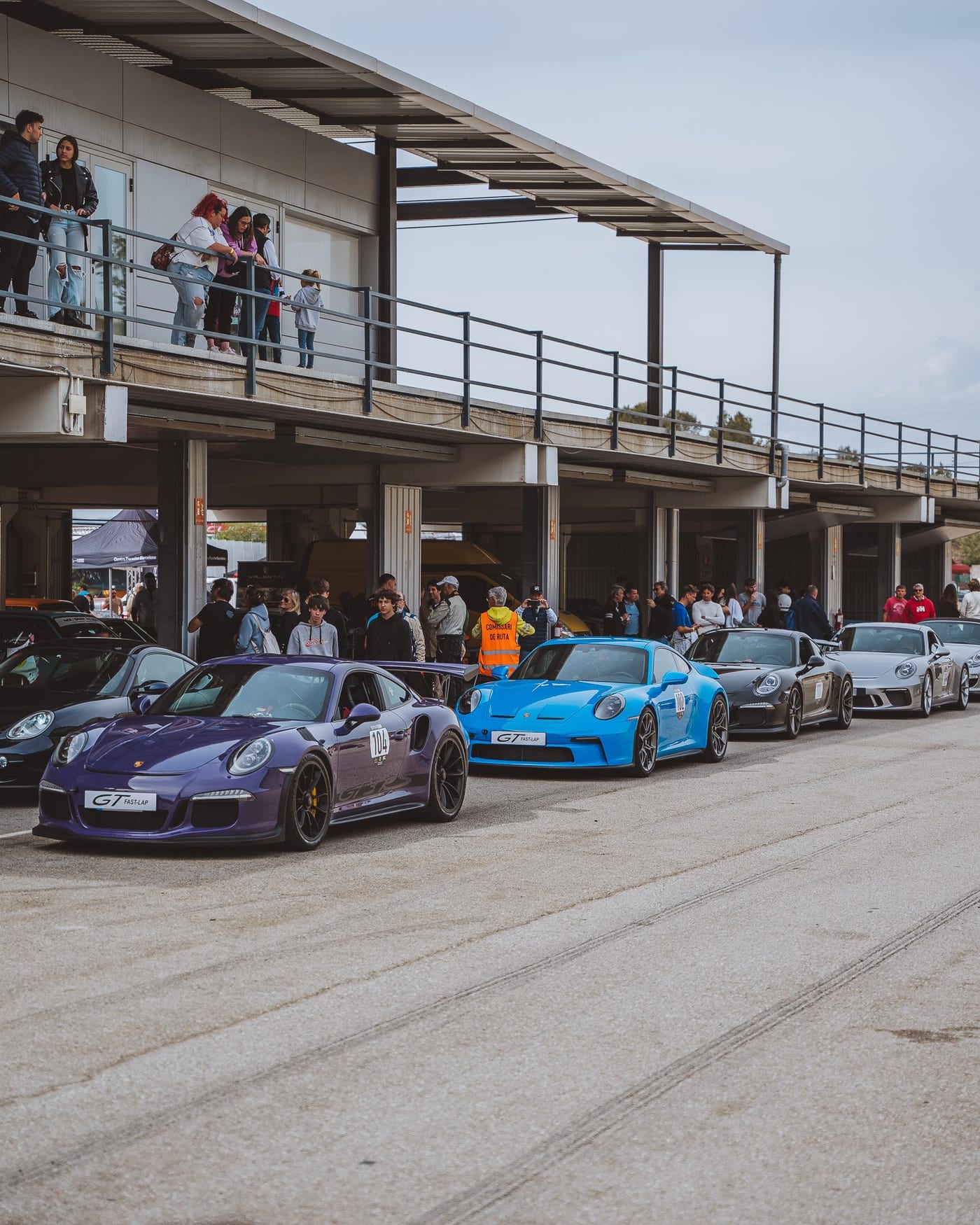 El pit lane de la Porsche Classic Series con los coches en fila y el público en la terraza