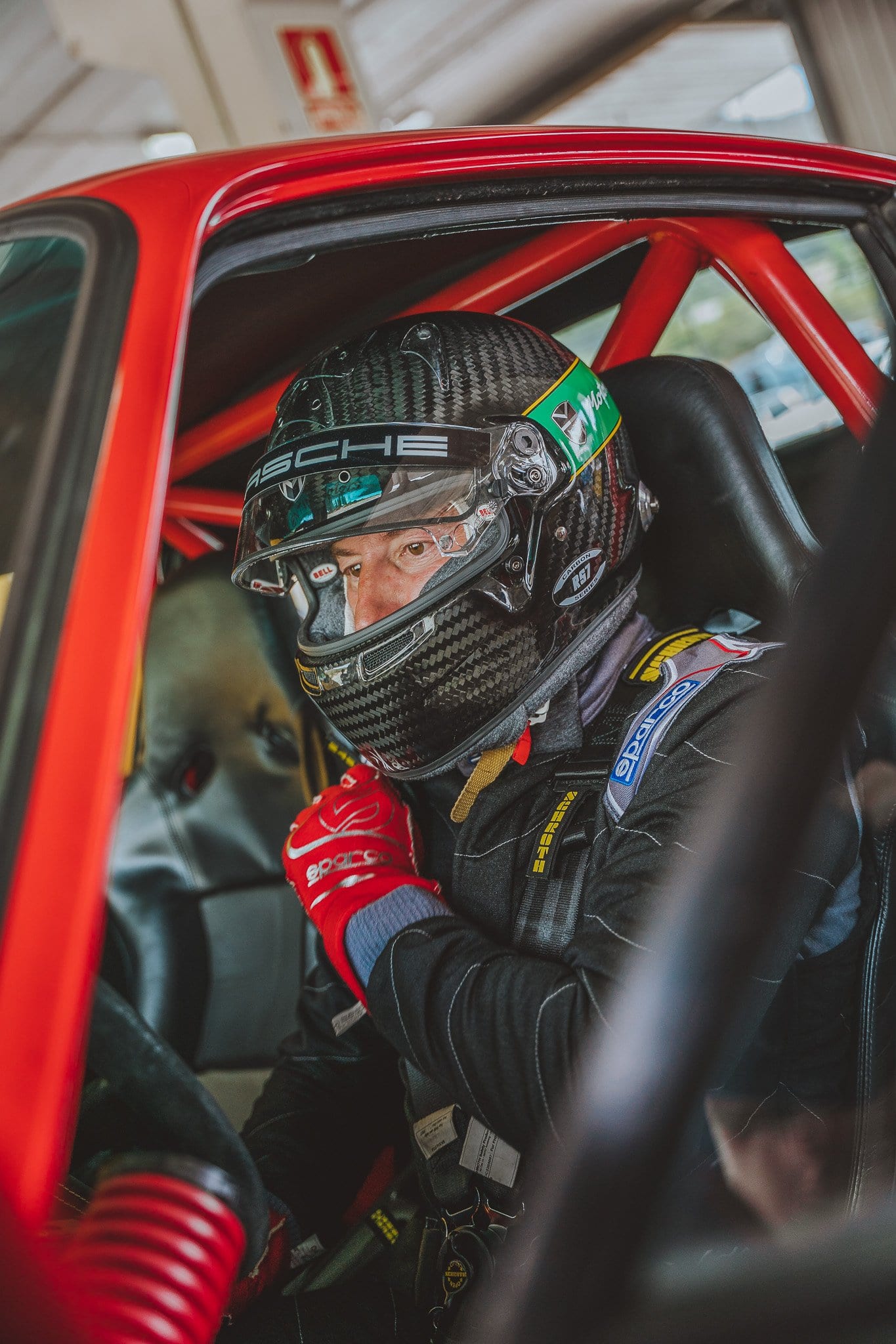 Primer plano del piloto con casco y guantes rojos al volante del 964