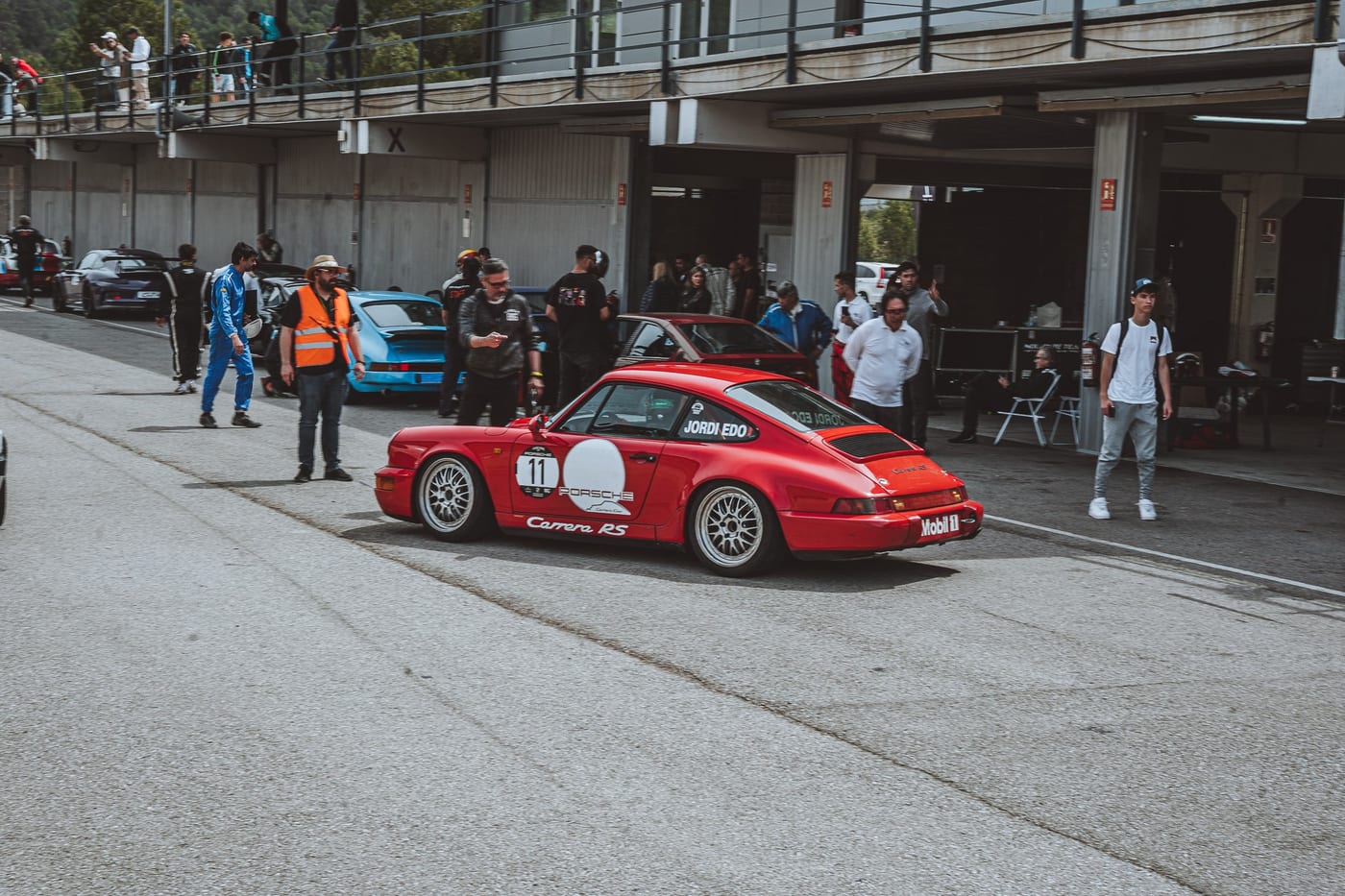 El 964 Carrera RS número 11 avanzando por el pit lane entre el público