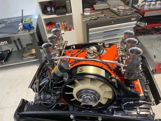 Motor bóxer con carburadores de doble cuerpo y chapa naranja, listo en el banco