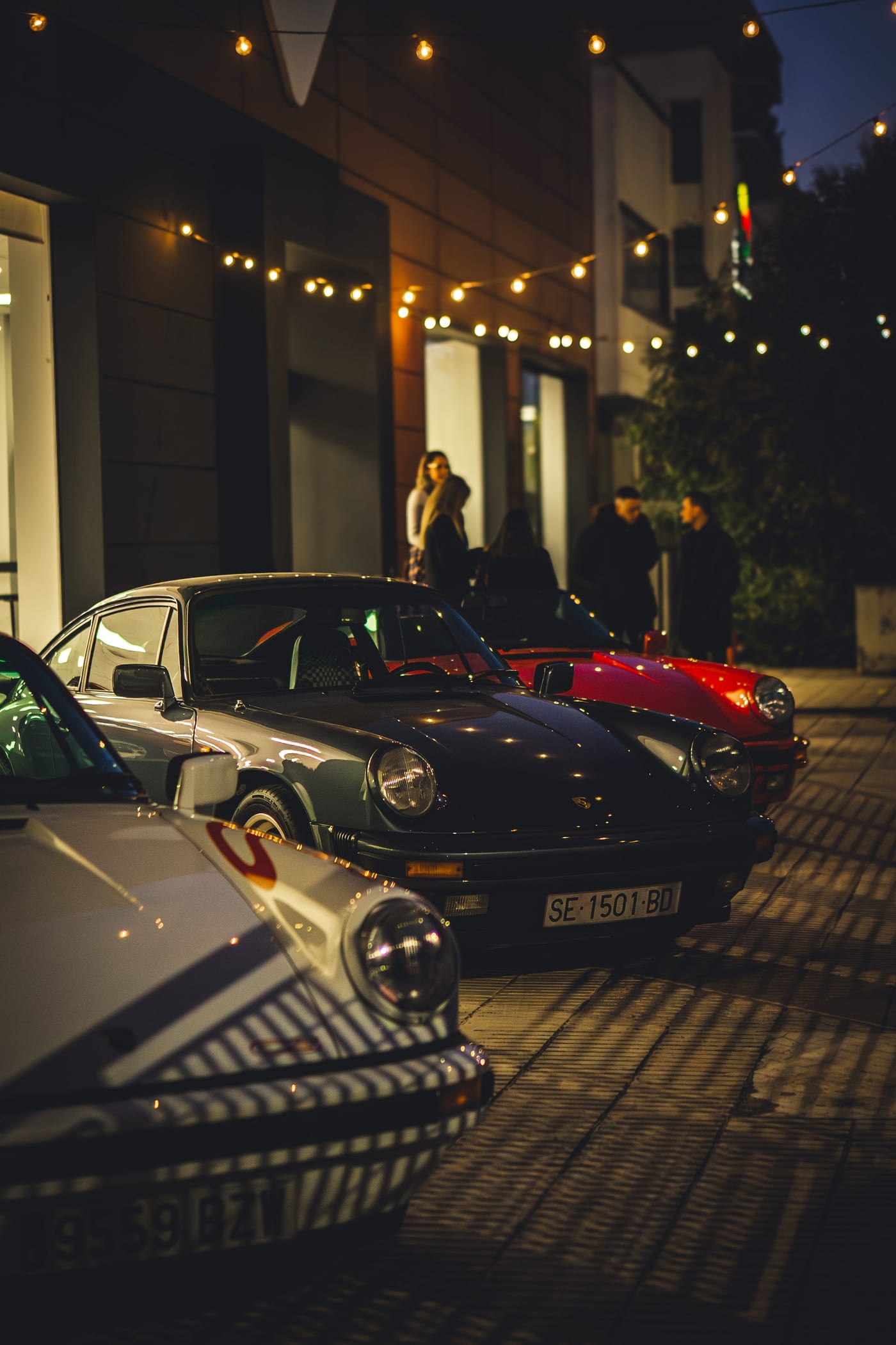 Due 911 parcheggiate di notte sotto le luci di una terrazza