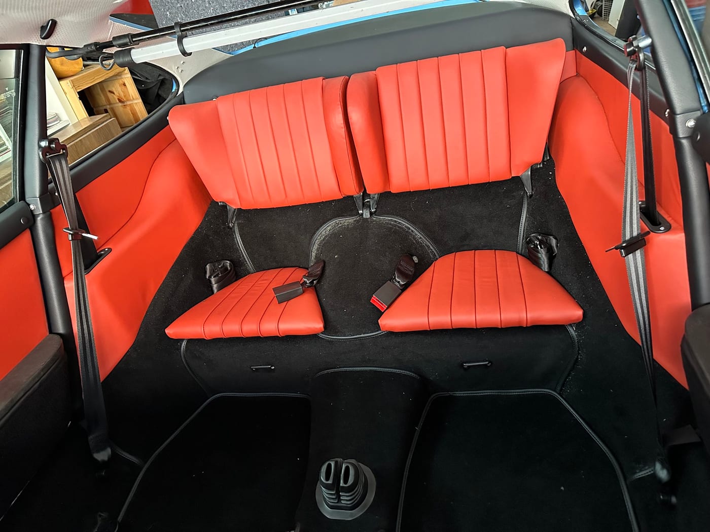 Banquette arrière de la 930 Turbo regarnie en cuir rouge, avec les ceintures