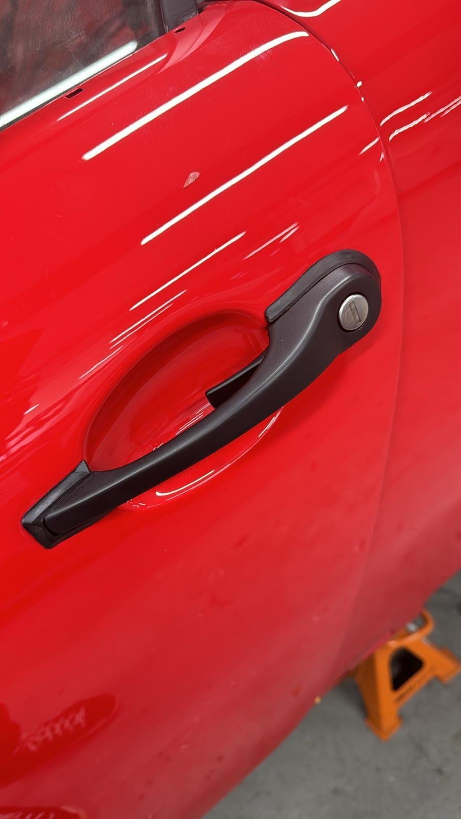 Detalle del tirador de puerta sobre la carrocería roja del 964