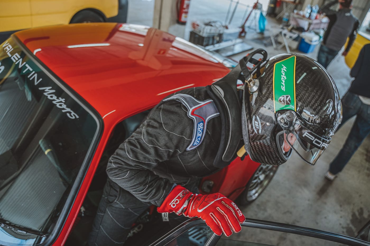 El piloto se inclina sobre la ventanilla del 964 rojo, con los guantes puestos