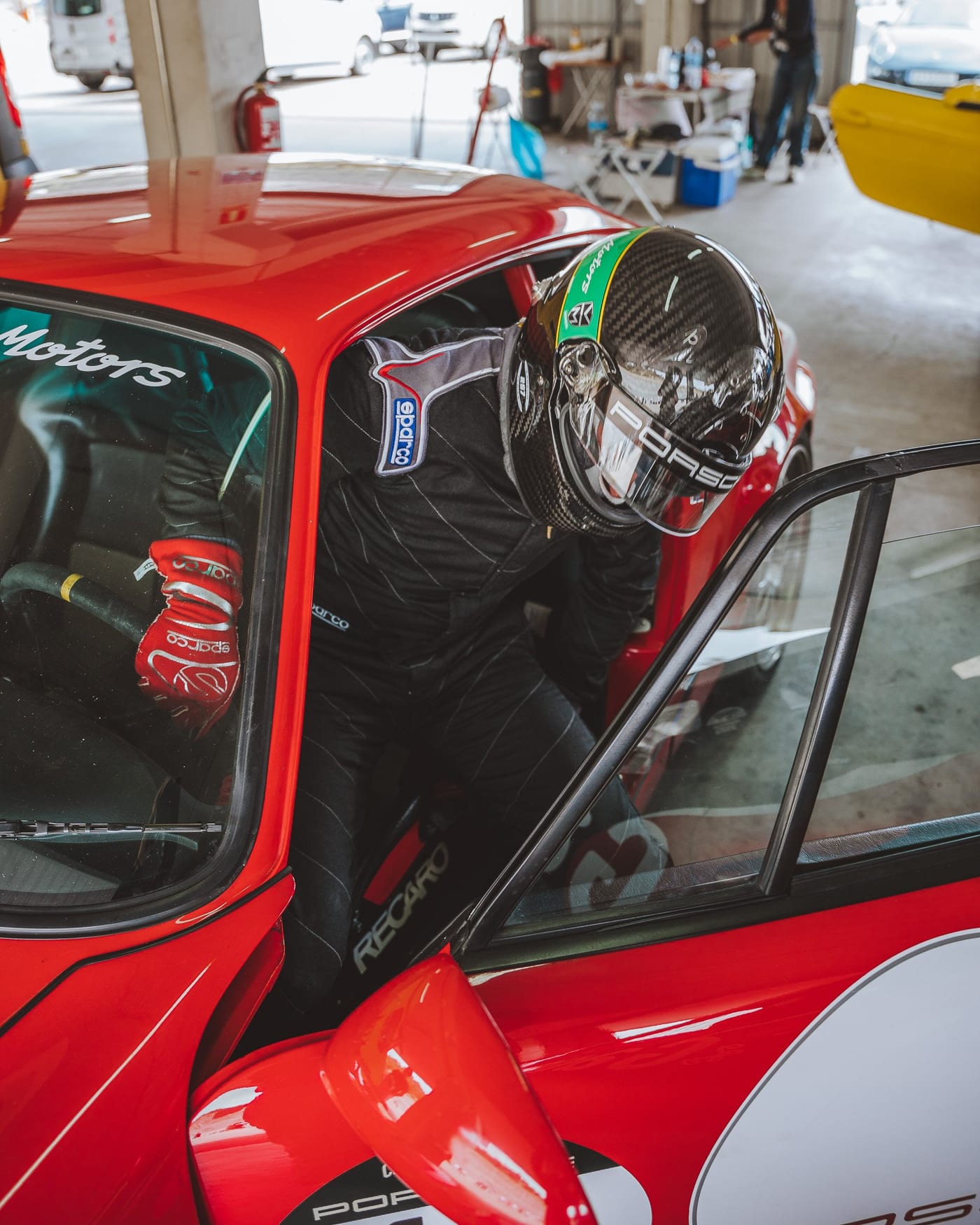 El piloto se dispone a subir al 964 rojo, con el asiento Recaro a la vista
