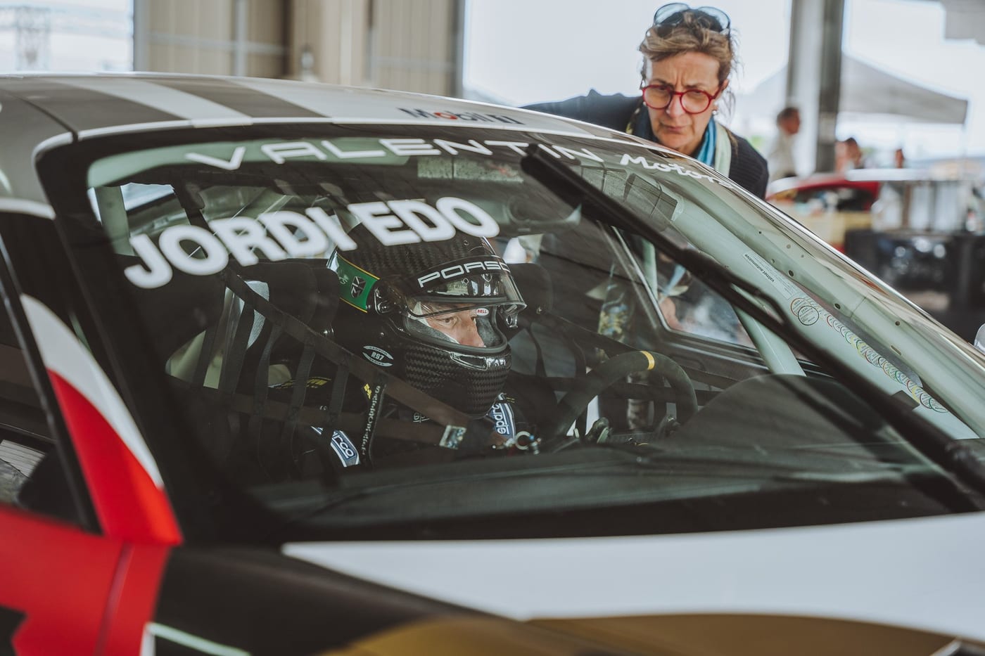 El piloto dentro del 991 Cup mientras una espectadora se asoma al parabrisas