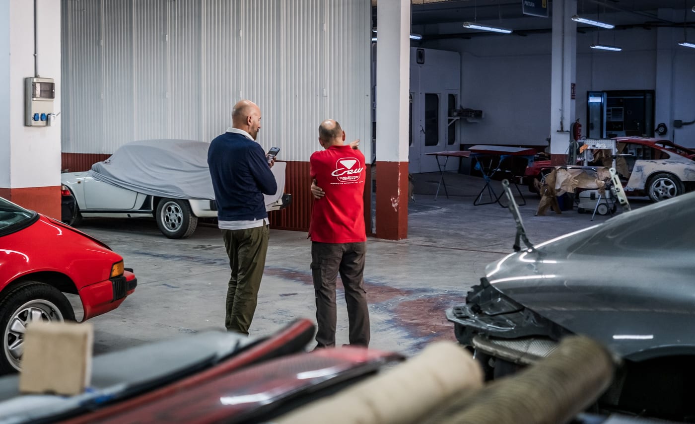 Dos personas conversan en la nave del centro de Leganés, con un coche cubierto al fondo