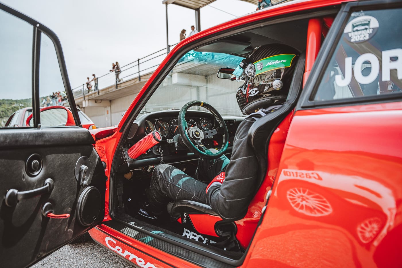 Habitáculo del 964 de competición con el casco en el asiento y la puerta abierta