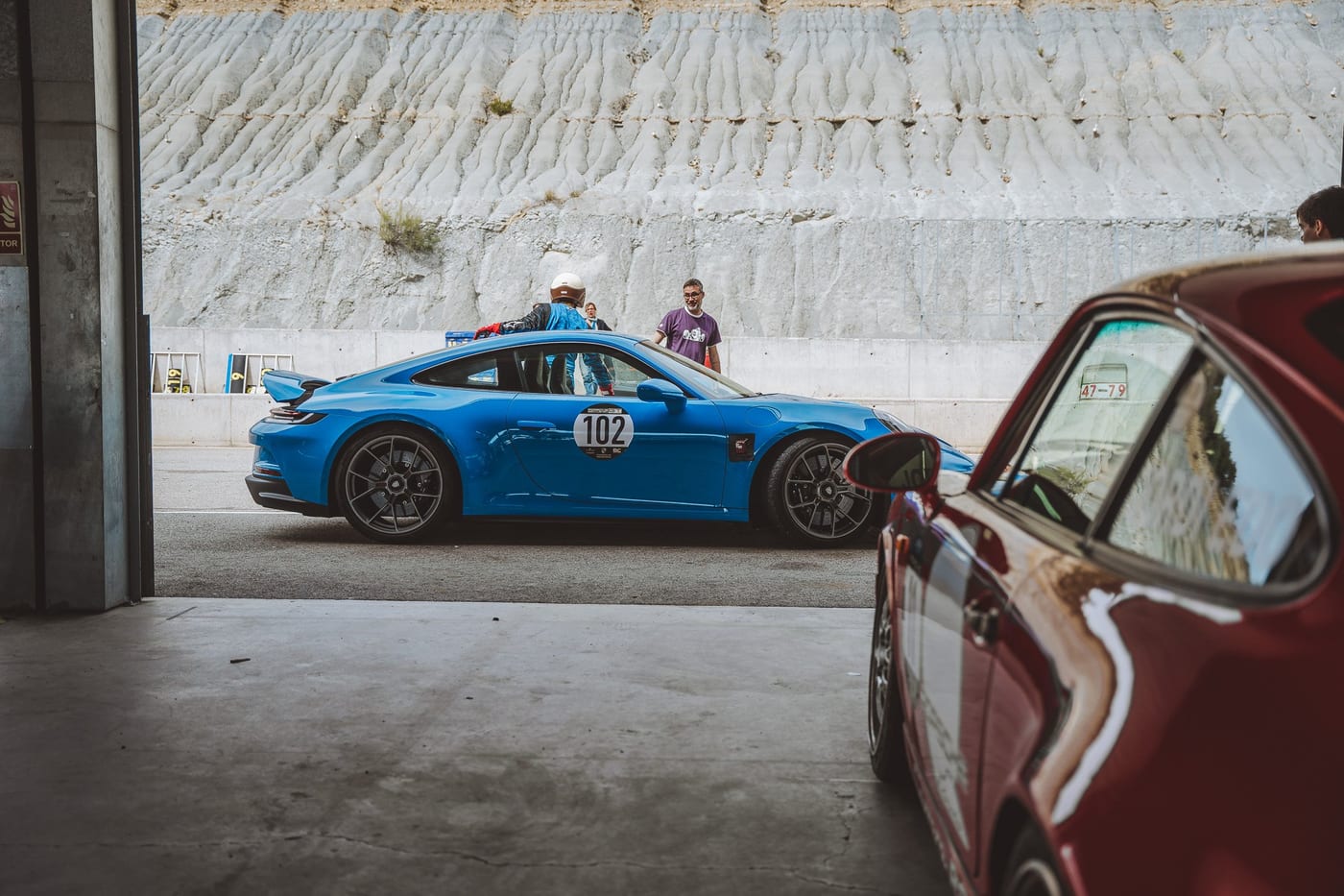 Un 992 azul con el dorsal 102 en el pit lane, visto desde el box