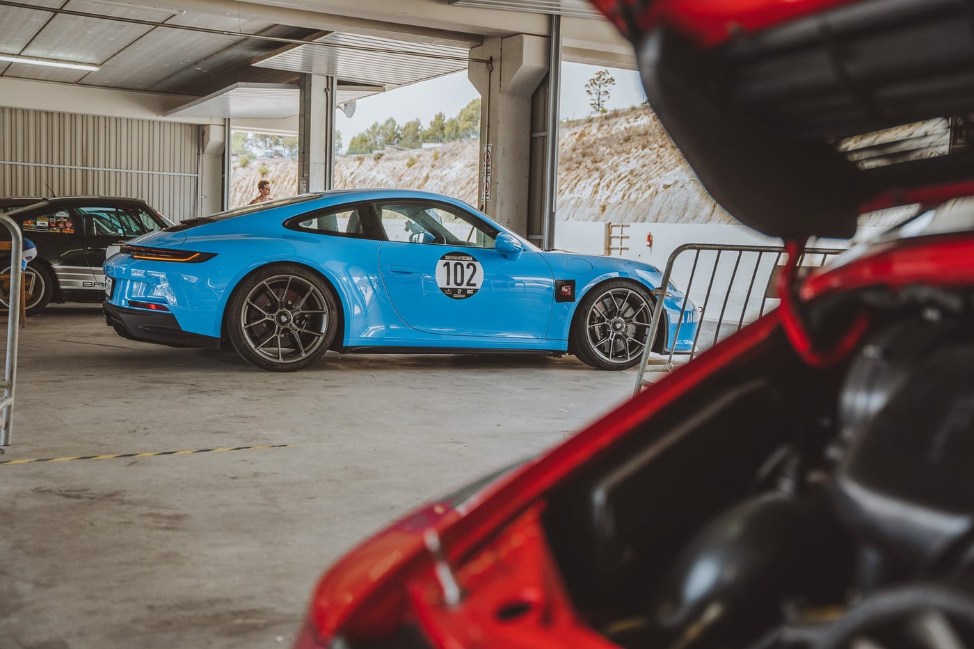 Un 992 azul con el dorsal 102 en el paddock, visto desde el motor abierto del 964