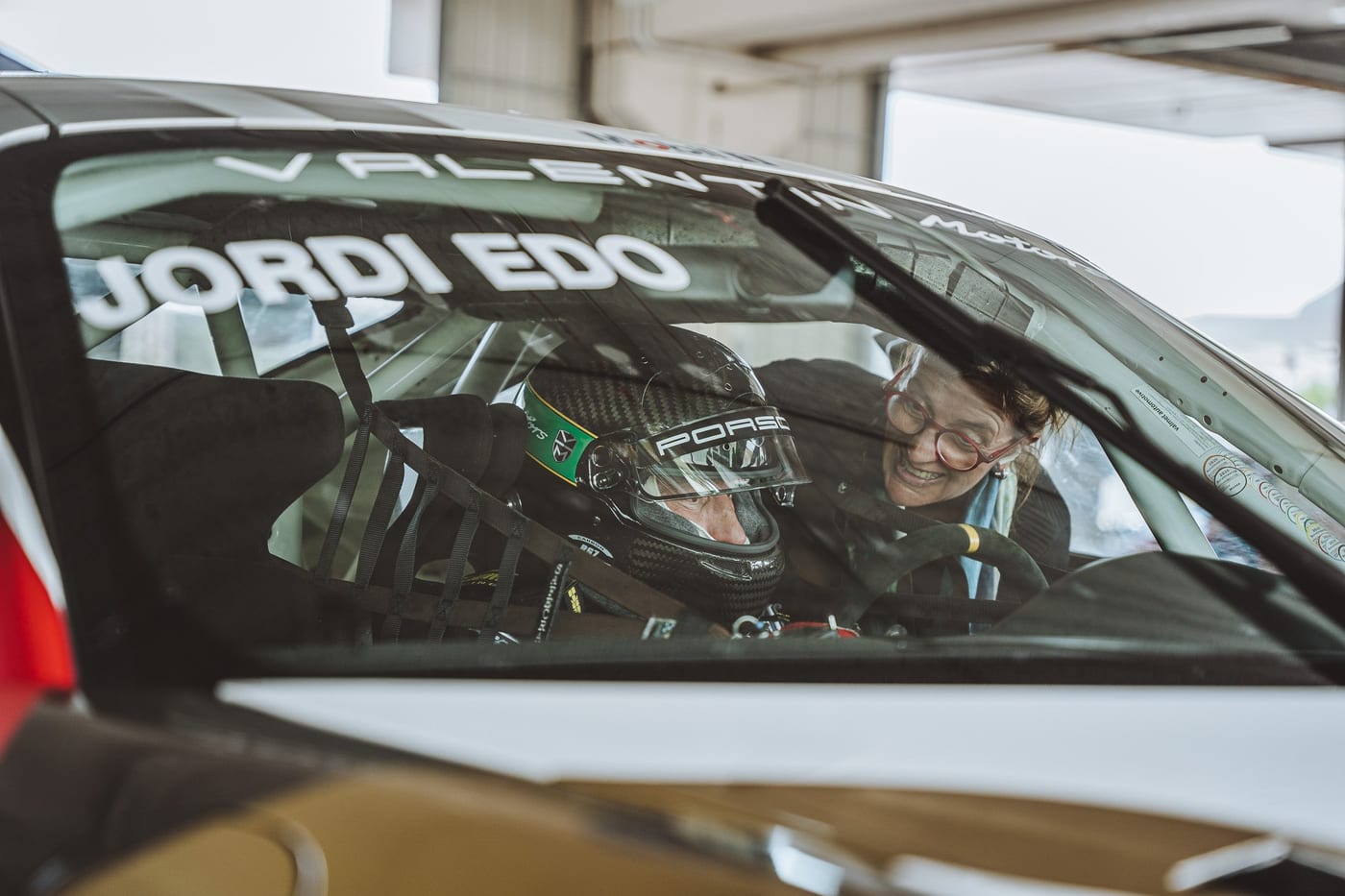 Primer plano del piloto con el casco dentro del 991 Cup, tras el parabrisas rotulado
