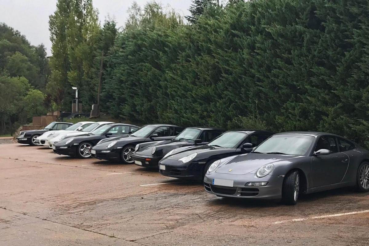 Els Porsche del VI Endurance aparcats en filera al costat d'una tanca, amb pluja recent