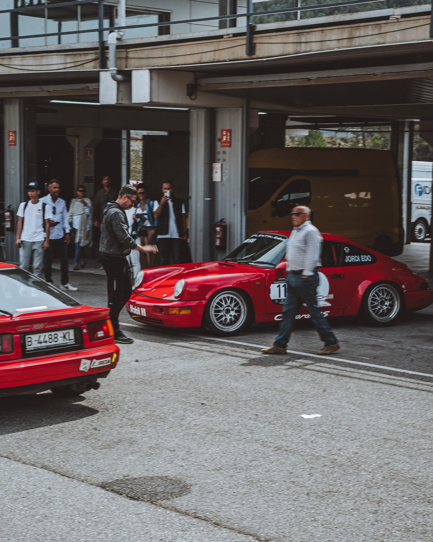 El 964 rojo de vuelta al box tras la manga, con la gente cruzando el pit lane