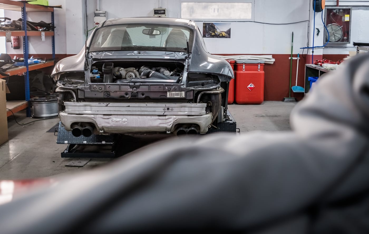 Porsche 911 grise, compartiment moteur ouvert, sur le pont de l'atelier de Leganés