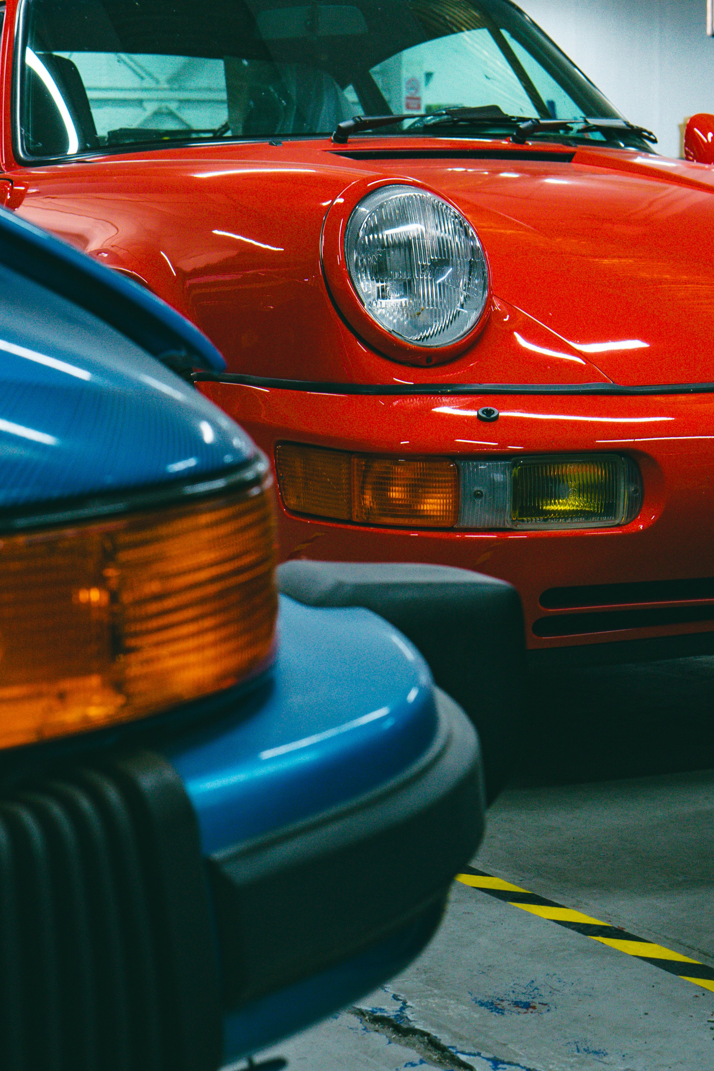 Frontales de un 964 rojo y un 911 serie G azul aparcados uno junto a otro en el Storage