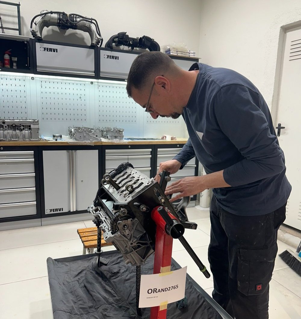 Mecánico trabajando sobre un bloque motor en el soporte giratorio de la sala de motores