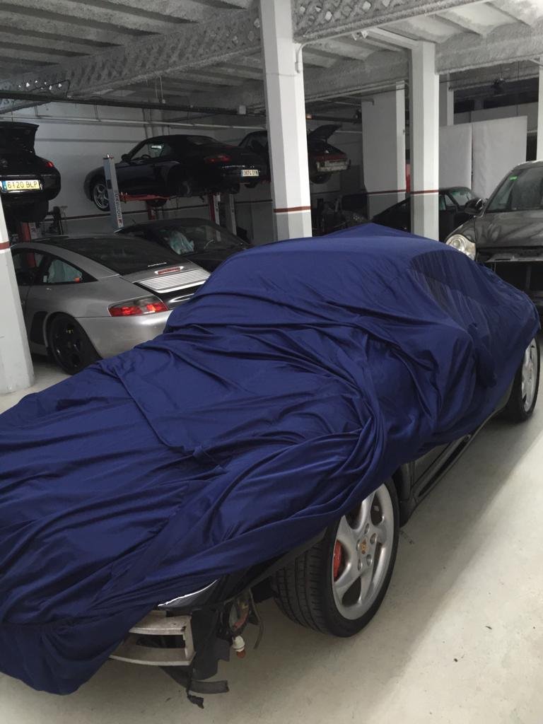 Porsche 964 cubierto con una funda azul en el taller, al inicio de un proyecto de backdating