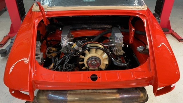 Motor 2.2 recién montado en el vano de un 911 serie F rojo de 1970, con la carrocería sobre el elevador