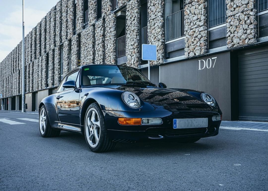 Porsche 911 993 azul oscuro de tres cuartos delante del taller