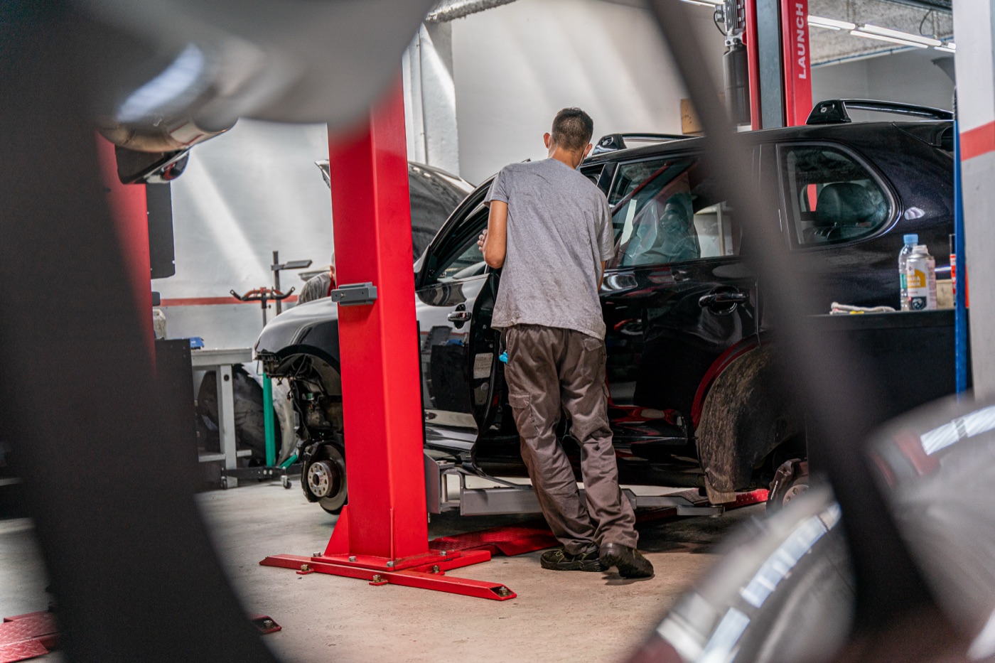 Mecánico trabajando en un Porsche 911 negro sobre el elevador
