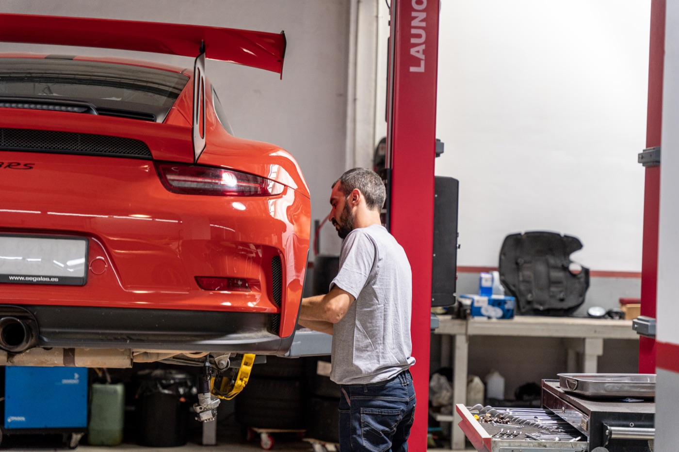 Mechanic next to a red Porsche 911 GT3 RS on the lift