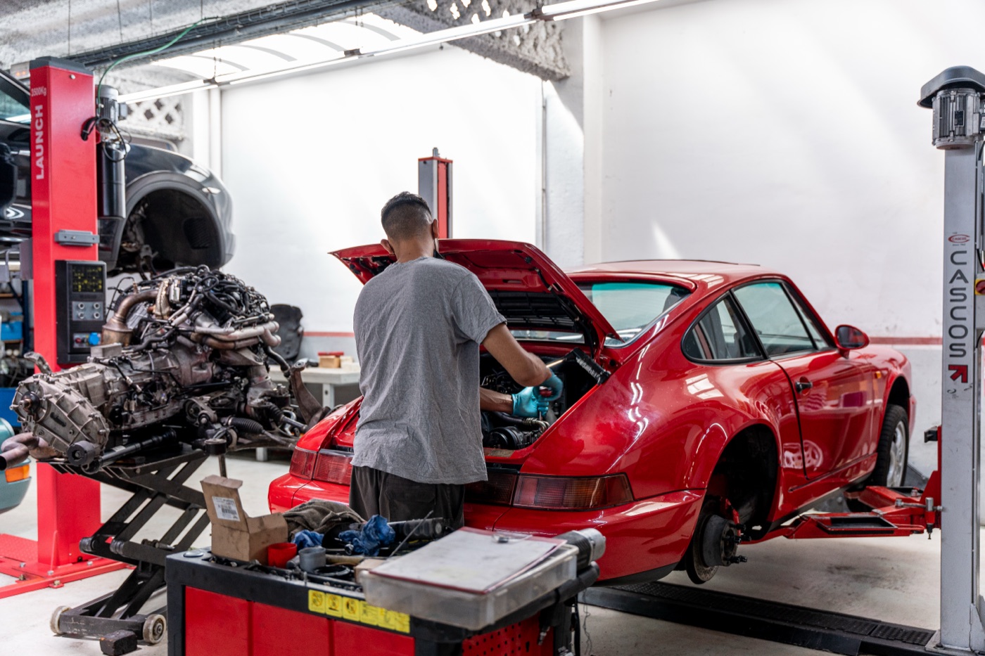 Mecànic treballant al vano motor d’un Porsche 964 vermell