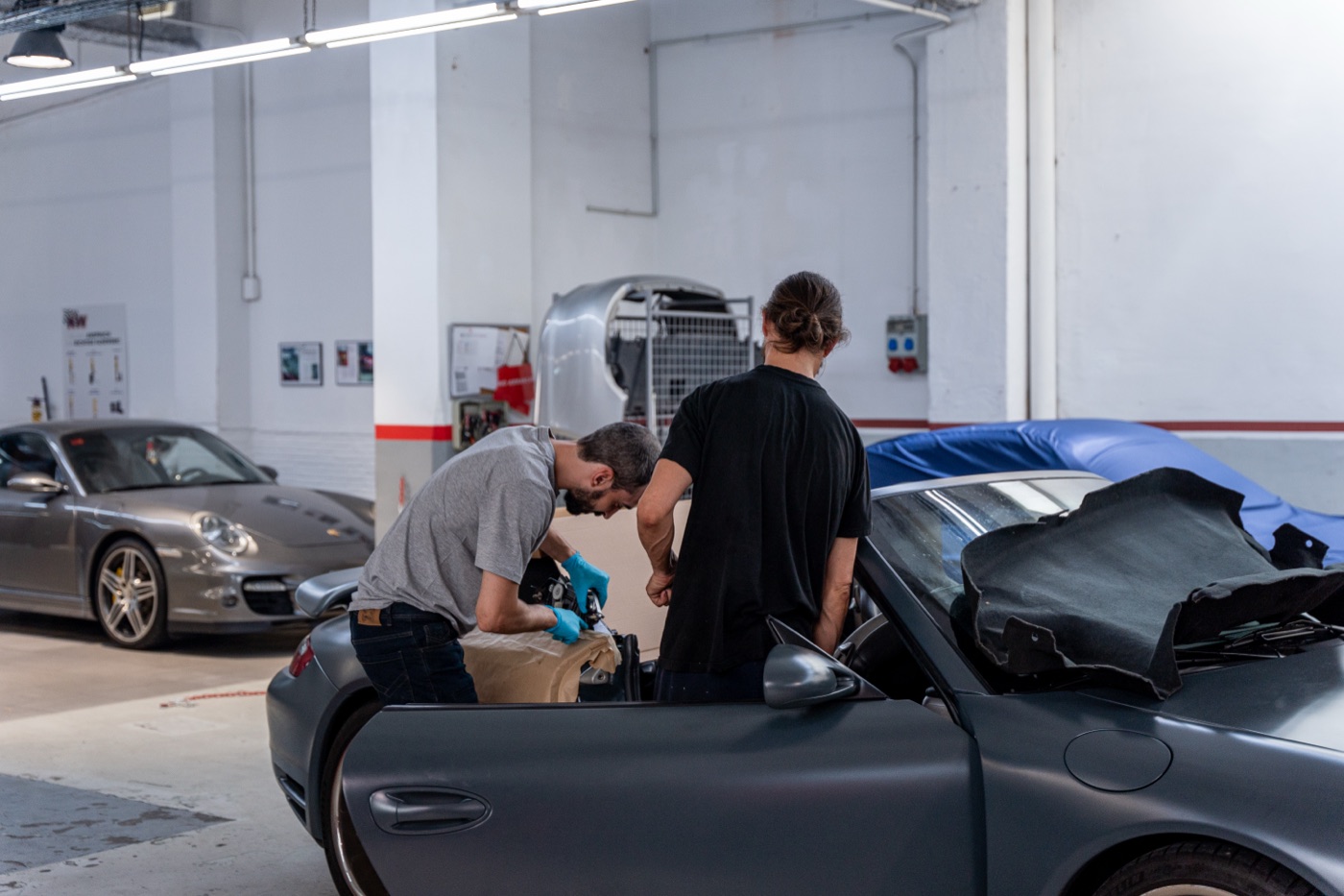Zwei Mechaniker prüfen ein Porsche Cabriolet in der Werkstatt